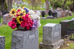 Flowers on a tombstone in a cemetery with headstones in the background