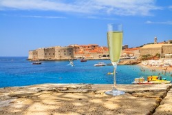 Coastal summer landscape - view of a wineglass of champagne against the background of the Old Town of Dubrovnik on the Adriatic coast of Croatia