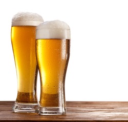 Two beer glasses on a wooden table. Isolated on a white background.