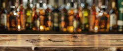 Wooden board and beautiful bokeh shelves with alcohol bottles at the background. Bar concept. Clipping path.