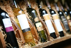 Closeup shot of wine shelf. Bottles lay over straw. Wine cellar.