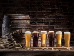 Glasses of beer and ale barrel on the wooden table. Craft brewery. Beer background.