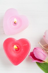Red pink heart candles and tulips on a white shabby wooden background and empty space for text. Top view with copy space