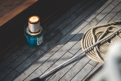 Paint cans standing on old wooden boat deck next to a rope, view from above, old aged ship