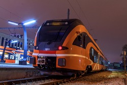 New modern orange train at night, photos from the side. Empty station without anybody standing on the platform. European transport electricity.