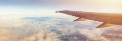 Flight wing panorama with copy space. Aircraft wing above the earth and clouds. Flight in sky. Travel by airlines for vacations.