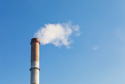 Pipe with white smoke against the background of blue sky and copy space