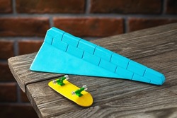 A blue triangular gypsum ramp and a yellow fingerboard on a wooden table