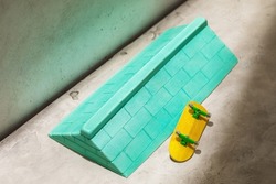 Green plaster ramp with brick wall texture and yellow fingerboard on abstract background