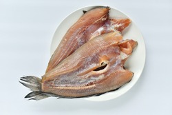 Sun-dried snakehead fish in a white plate on a white background