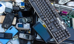 Close up on pile of mixed electronic waste, old broken computer parts and cell phones