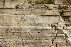 Texture, layers and cracks in sedimentary  rock on cliff face.