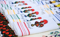 Souvenir towels with embroidery of the Galo de Barcelos (Barcelos Rooster) -  traditional symbol of Portugal - at the street market in Porto (Portugal). Selective focus on the closest towel.