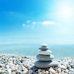 zen-like stones on beach and sun in sky. soft focus on bottom