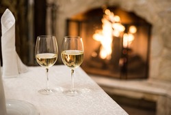 two glasses of white wine with fire reflection