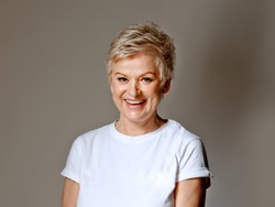 Mature grey haired  woman wearing white T-short posing. photo real woman without retouching.  Facial wrinkles and texture.