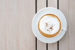 Cappuccino or latte with frothy foam, coffee cup top view on wooden background. Cafe and bar, barista art concept.