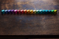 Colored wooden blocks aligned on old vintage wooden table. For something with concept of variations or diversity. Plenty of copyspace. Shallow depth of field.