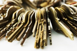 Many brass and chrome old keys on white table. Security and encryption, concept image.