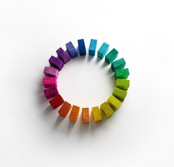 Color wheel of wooden blocks. Colors of unity. Circle of colored blocks representing unity of diverse elements. Wooden blocks placed in a a circle on a neutral white background, with natural shadows. 