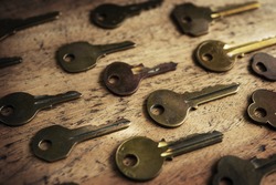 Various vintage brass keys aligned in the same direction on a old wooden desk. Security and encryption, concept image. 