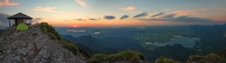 herzogstand mountain top with view to bavarian foothills and several lakes at sunset. Pavilion and camping tent at the summit.