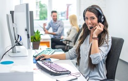 Portrait of happy smiling female customer support phone operator at workplace.