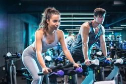 Attractive woman and handsome man doing spinning on cycling bikes