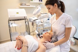 Female patient enjoying rejuvenation procedure performed by a therapist in a beauty clinic