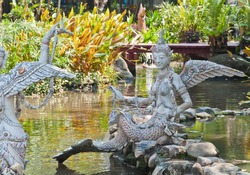 The Gandharvas in Thai style which mixed between woman, bird and fish made from cement and decorated by tile on the water