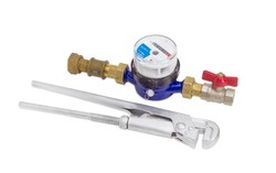 Residential mechanical water meter for consumption measuring of a cold water with some plumbing components and plumber wrench on a light background