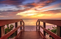 Boardwalk leading to a Sunset over North Gulf Shore Beach along the coastline of Naples, Florida