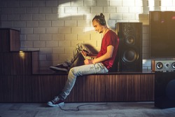 Handsome man, a music lover listens to music with headphones with mobile phone in a modern interior against the media and large speakers. Enjoying music is fun and communicates on the Internet at home