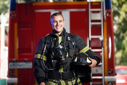 Photo of happy fireman with gas mask and helmet near fire engine