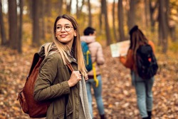 Portrait of young female hiker in forest with friends.