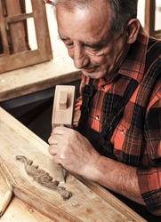 Senior carpenter restoring old furniture in his workshop