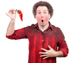 Man holding a spicy red paprika isolated on white background. The shock of hot chili peppers. Red face from eating hot vegetable. 