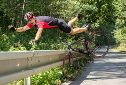 Cyclist falls off the bike into bushes. Accident on the road. Biker fall from the bike into the grass. Bicycle accident when falling through road barriers. Accident man in sports.
