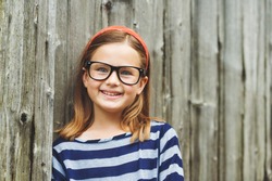 Outdoor portrait of a cute little 9 year old girl wearing eyeglasses