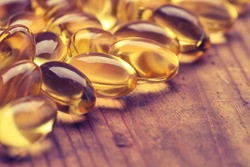 Cod liver oil omega 3 gel capsules isolated on wooden background. Vitamin D capsuls. dietary supplement