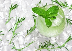 Refreshing drink with mint leaves in large wineglass surrounded by ice cubes. Close-up, top view. Cold mojito. Ice lemonade