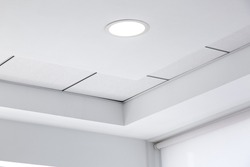 multi-level ceiling with three-dimensional protrusions and a suspended tiled ceiling with a built-in round led light in the corner of the room, close up details.