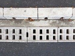 concrete grating drainage of an asphalt road with a curb, rainwater gratings on the road top view, nobody.