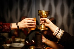 people clink by cups on a medieval feast.