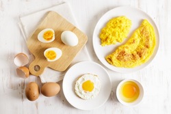 Cooking eggs in deferent way like boiled egg, fried egg and scrambled egg on wooden table. Top view.