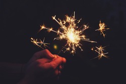 Man holds sparkler in the night.