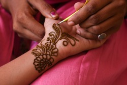 Artist applying beautiful henna tattoo Arabic design to a Woman's or Indian bride's hands at City Palace on wedding in Rajasthan. Mehndi is a popular body art among women of India, Pakistan, Africa.
