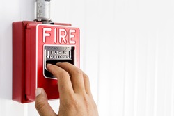 Fire alarm switch, The hand of man is pulling fire alarm on the wall next to the door,Fire alarm switch.Break glass and press button to activate. With hand and direction arrow, Hand push fire botton.