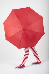 The girl standing behind a large red umbrella