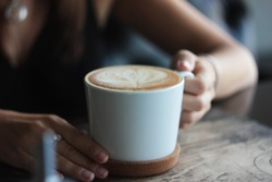 Large white Cup with cappuccino in female hands, selective focus